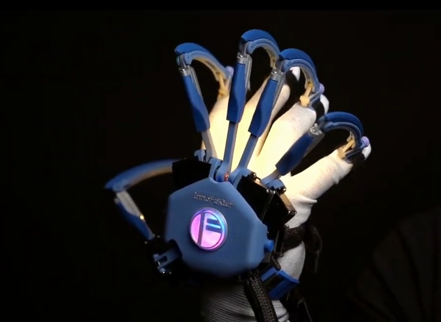Close-up of the FELYA haptic glove with blue finger mechanisms over a fabric glove.